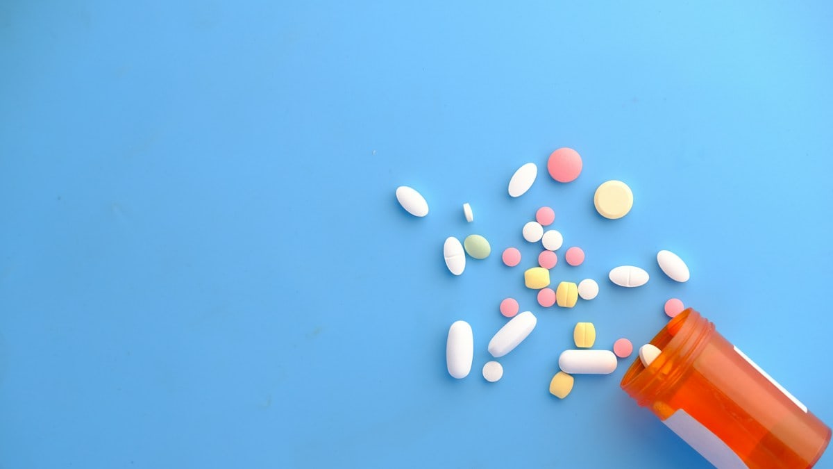 colorful pills spilling from orange bottle